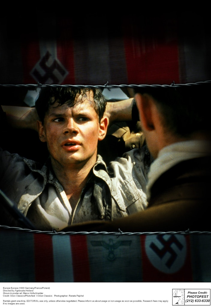 Young man held by soldier under Nazi flag.