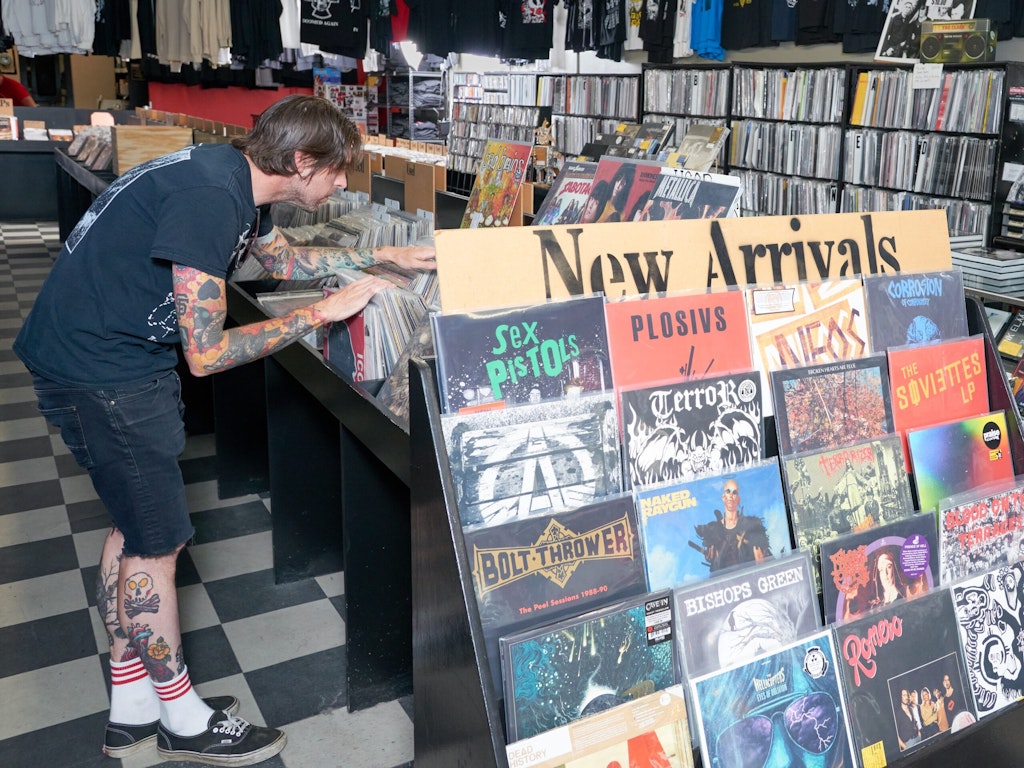 A man looks through racks of records next to a display case of records marked 