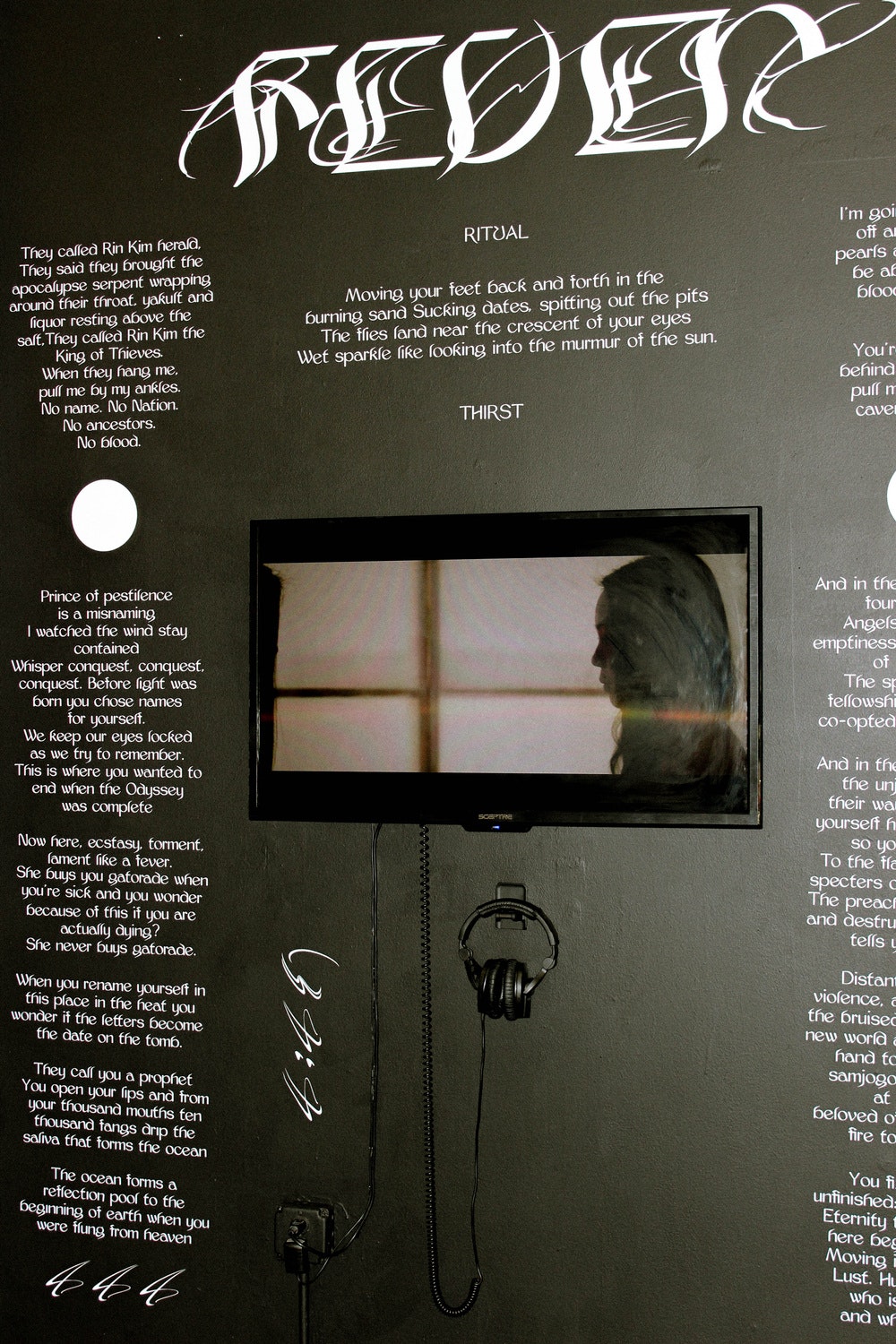 Installation of Fever with a television and various poems on a black wall