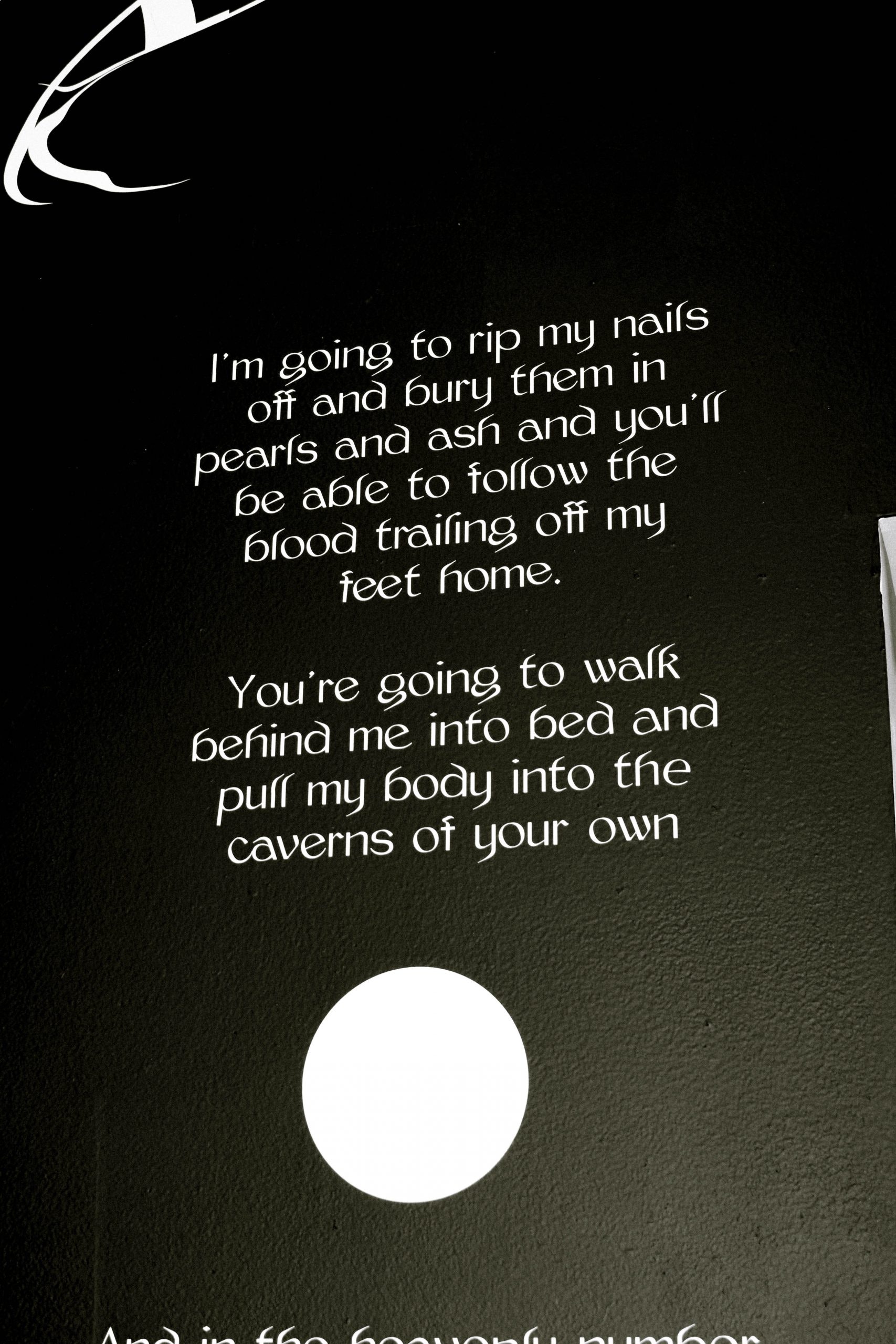 a poem adhered to a black wall in white vinyl 