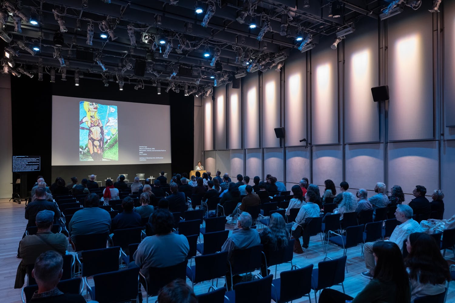 A group of people watch a projected images in a auditorium.