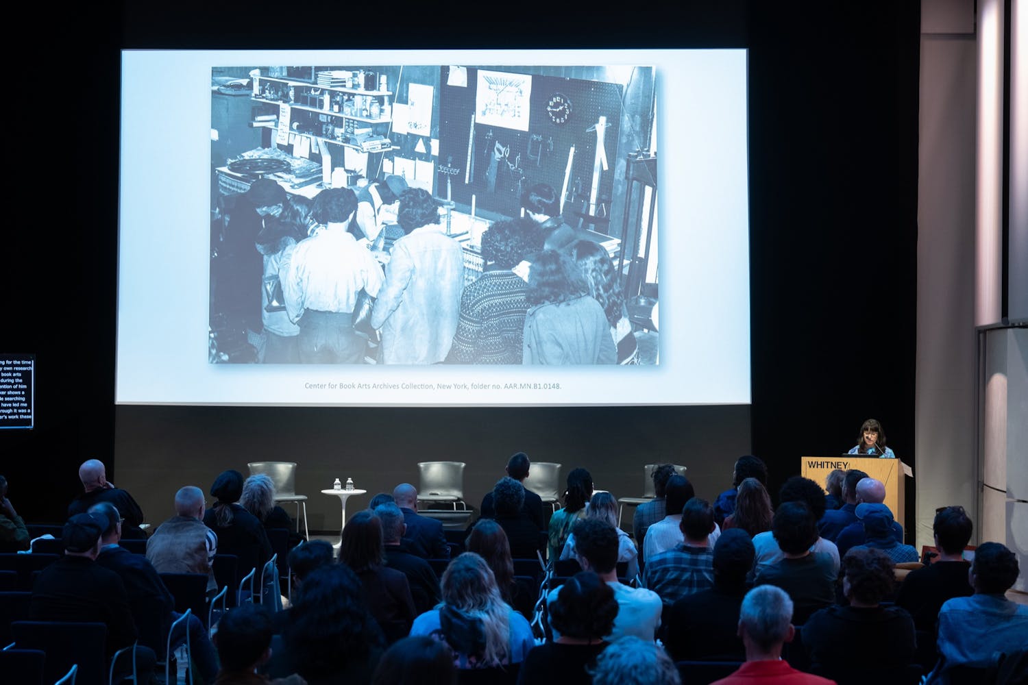 A group of people watch a projected images in a auditorium.