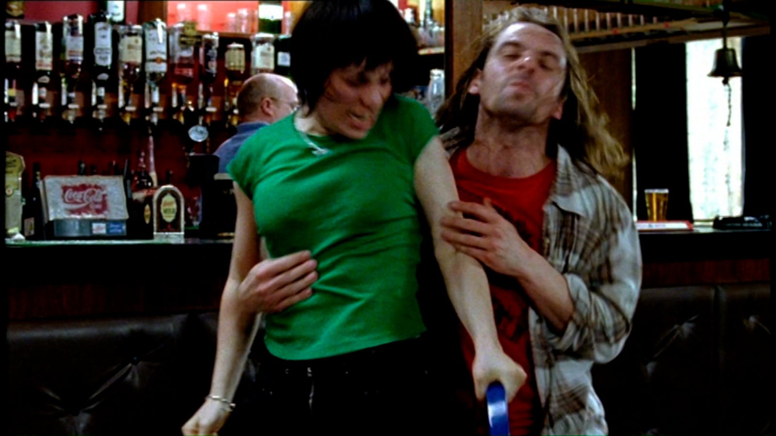 In a bar, pairs of people physically fight each other on either side of a wall, on the left and right sides of the image.