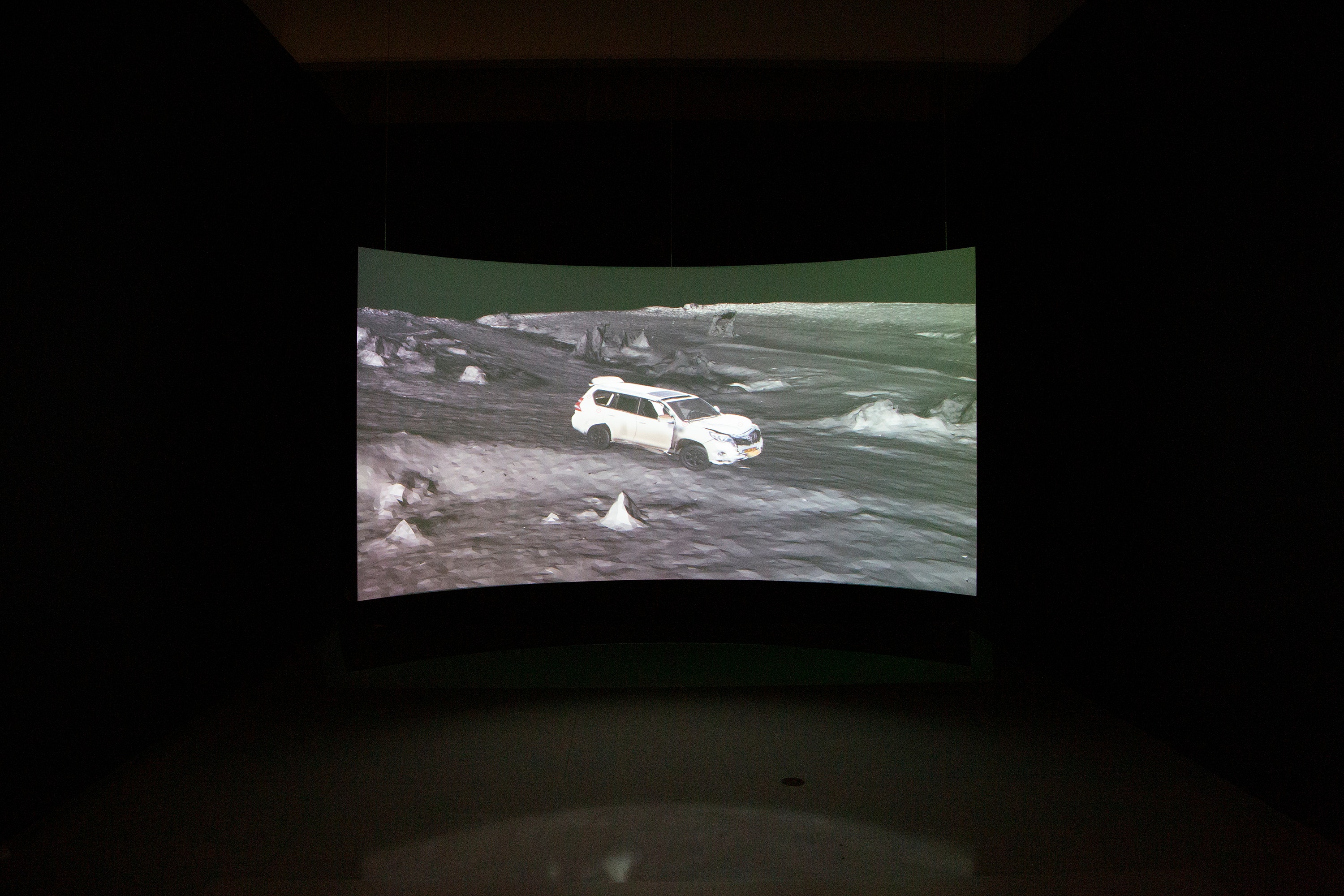 Image of curved projection screen featuring video stills of Forensic Architecture video