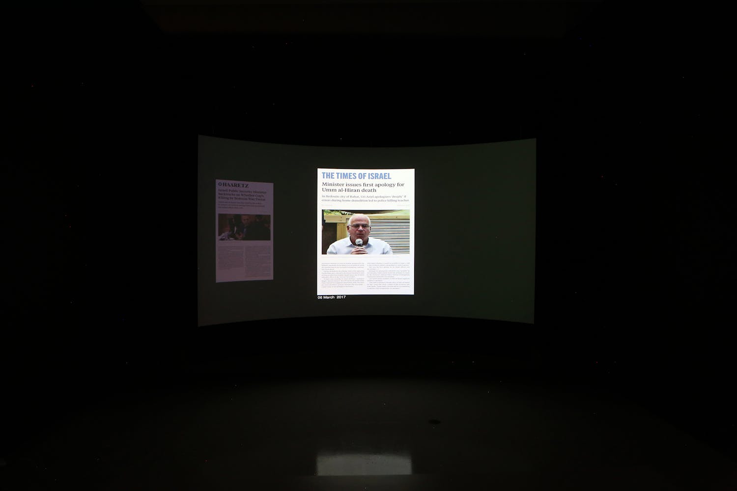 Image of curved projection screen featuring video stills of Forensic Architecture video