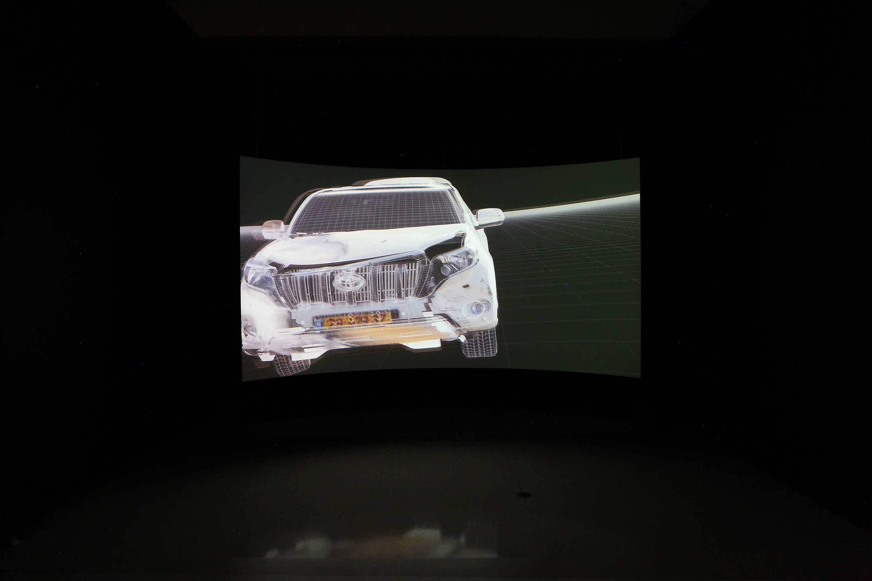 Image of curved projection screen featuring video stills of Forensic Architecture video