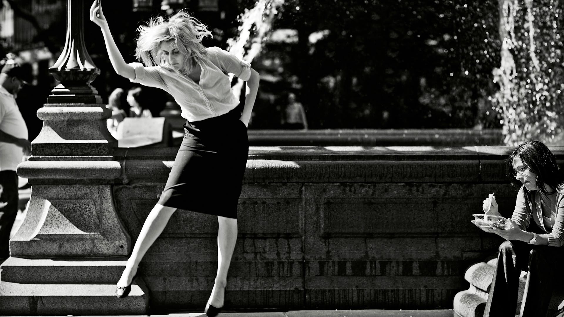 Black and white film still of Greta Gerwig playing Frances Ha dancing in front of a fountain in a park
