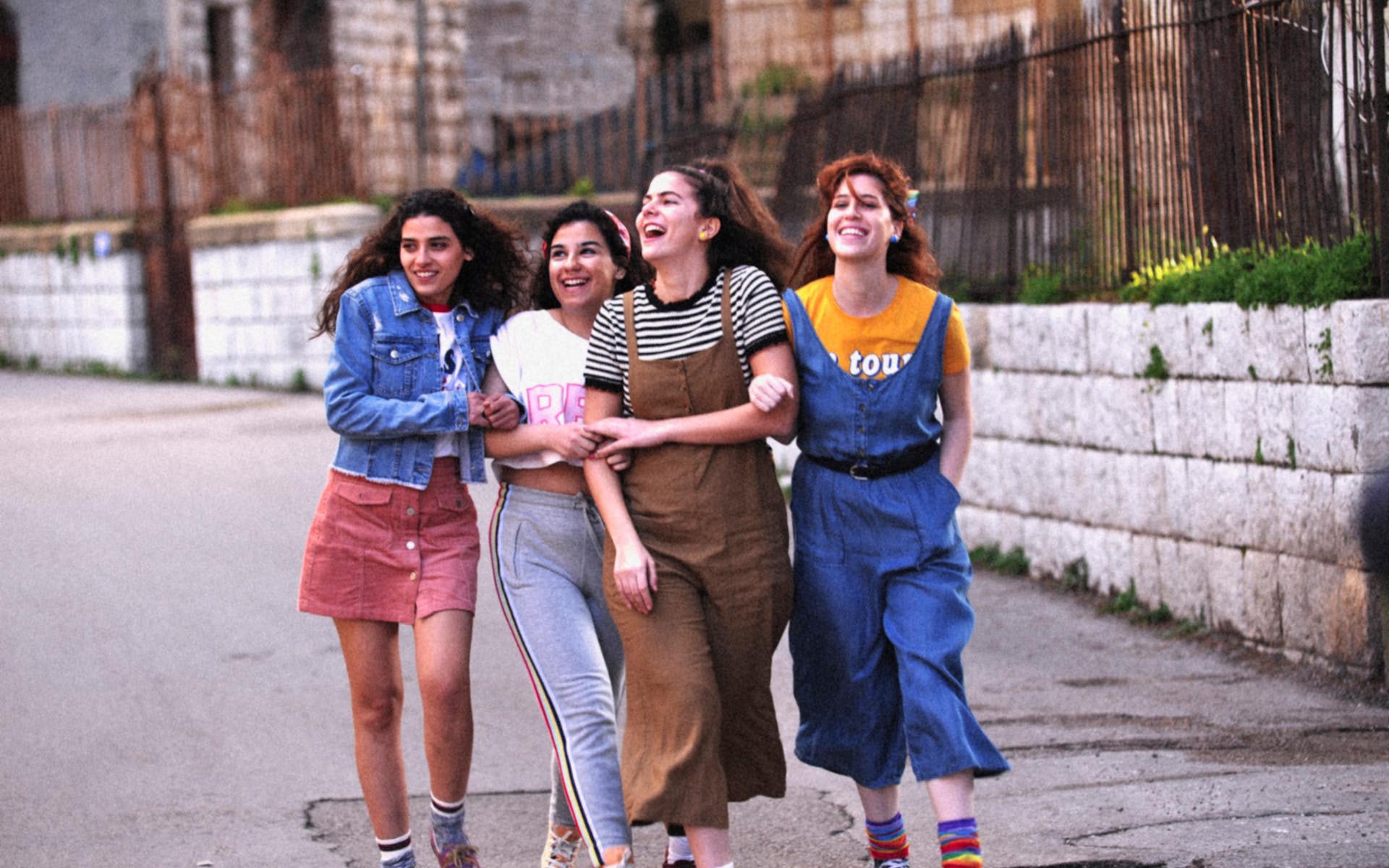 A goup of young women walk and laugh together on a city street.