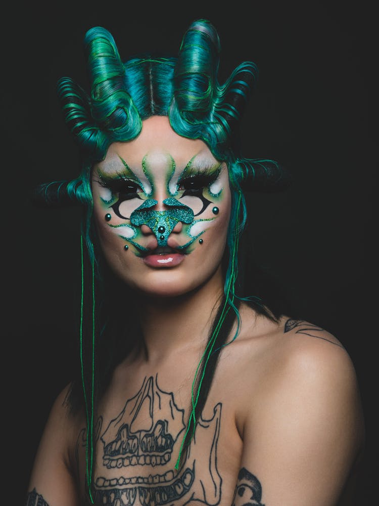 A person wearing geometric alien-like make-up looks at the viewer.