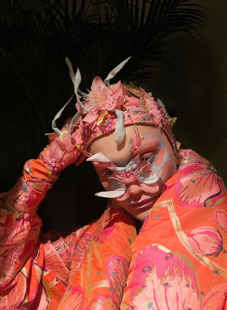 A person wearing geometric alien-like make-up looks at the viewer.