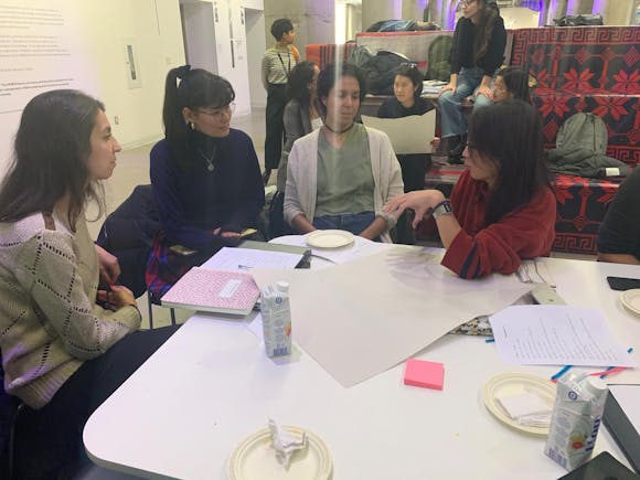 A group of adult women sit around a table talking