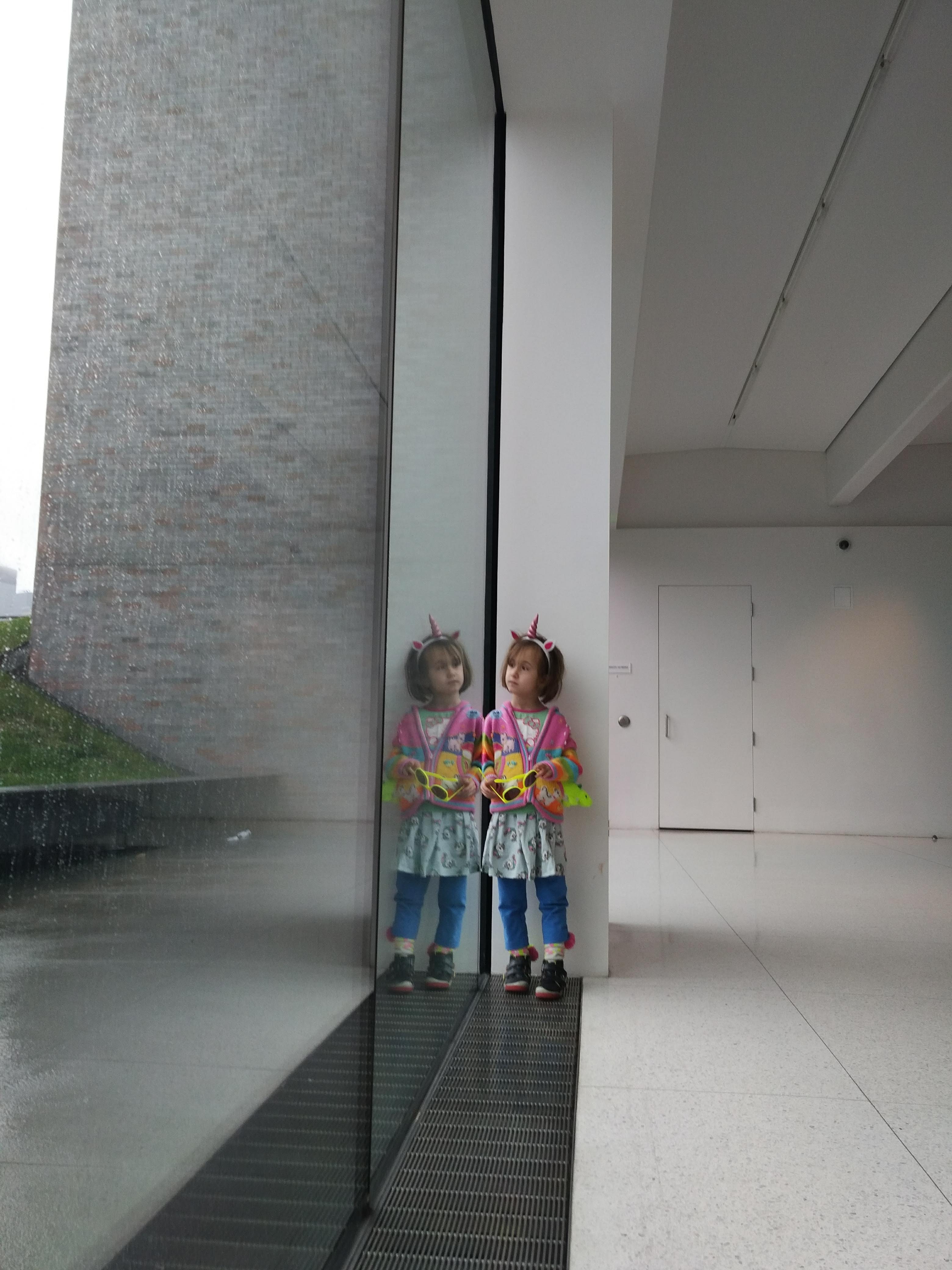 A girl stands at a window in the museum looking outside.