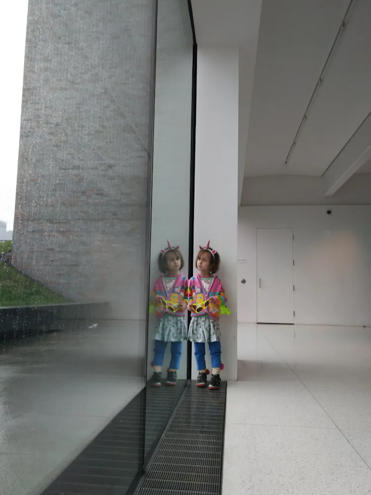 A girl stands at a window in the museum looking outside.