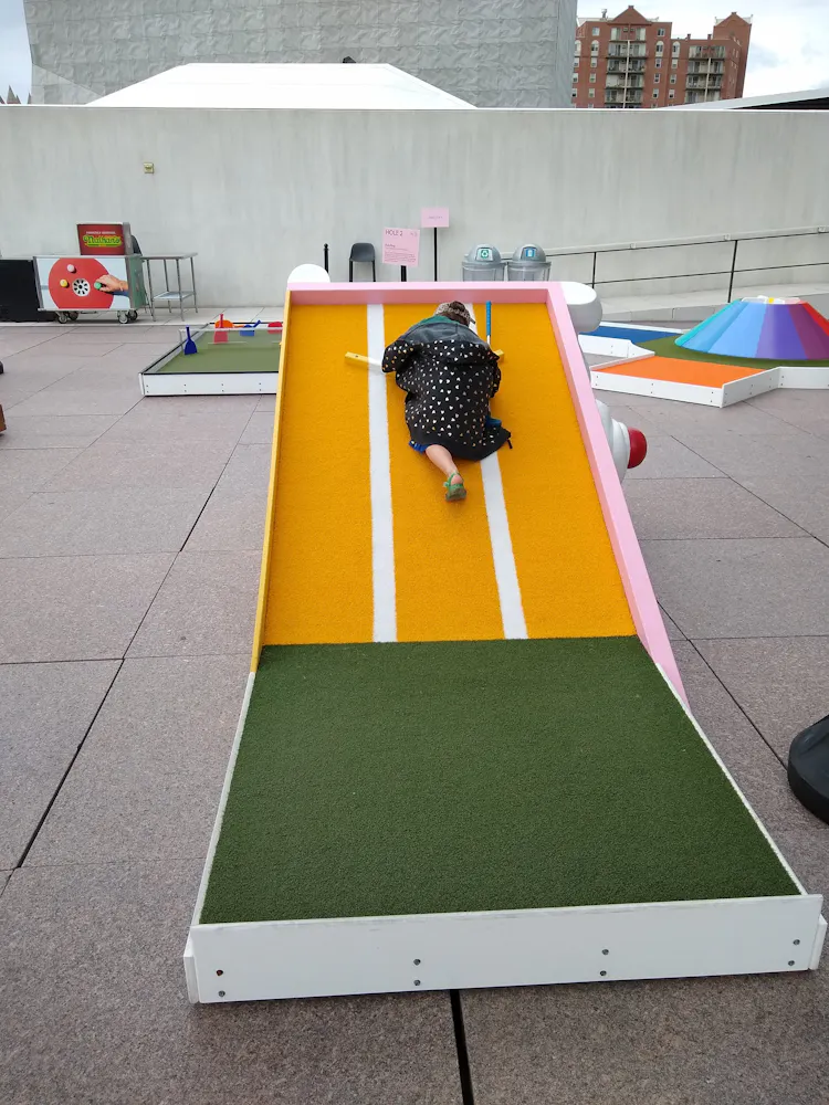 A girl lays down on a mini golf course