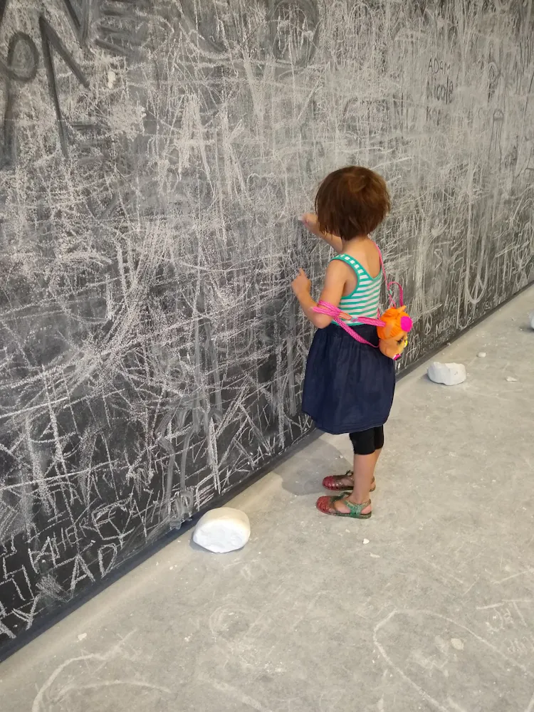 A girl draws on the walls of a gallery using chalk.