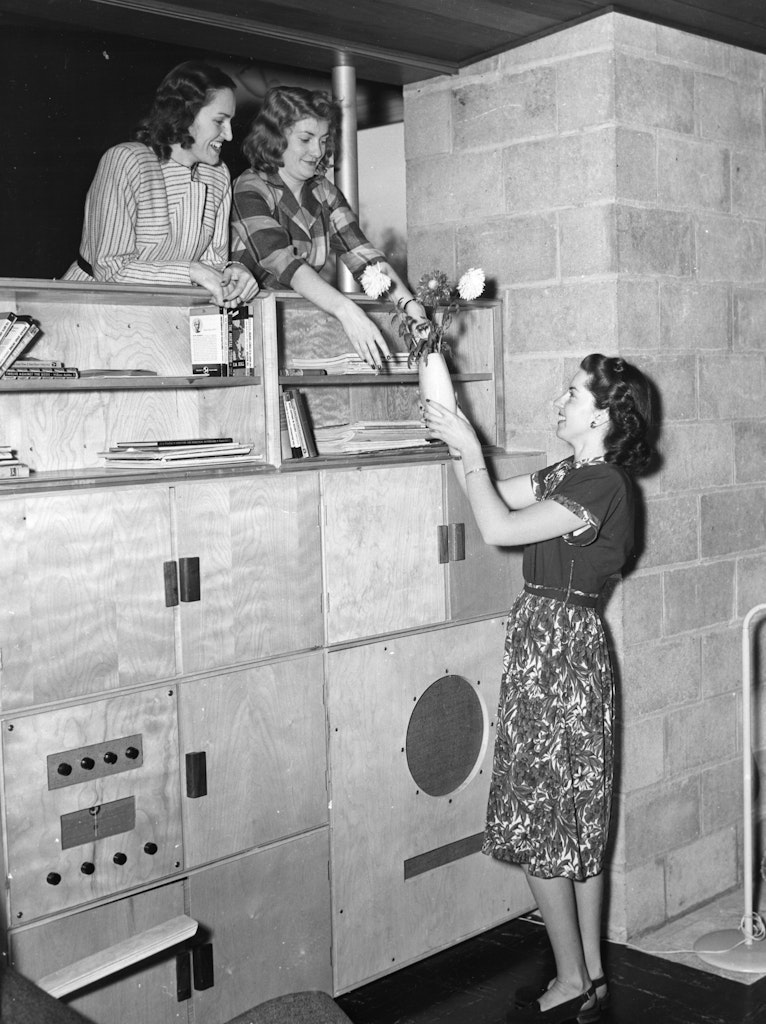 A black and white photograpgh of a three women with light skin sitting in the living room of a 1940s modernist home.