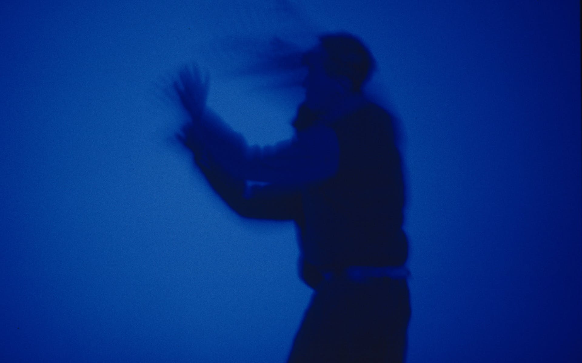 Silhouette of man in motion in front of blue screen