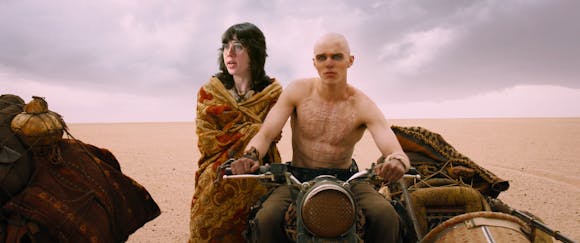 image from Mad Max of a man on a motorcycle in the desert, with a woman superimposed into the frame.