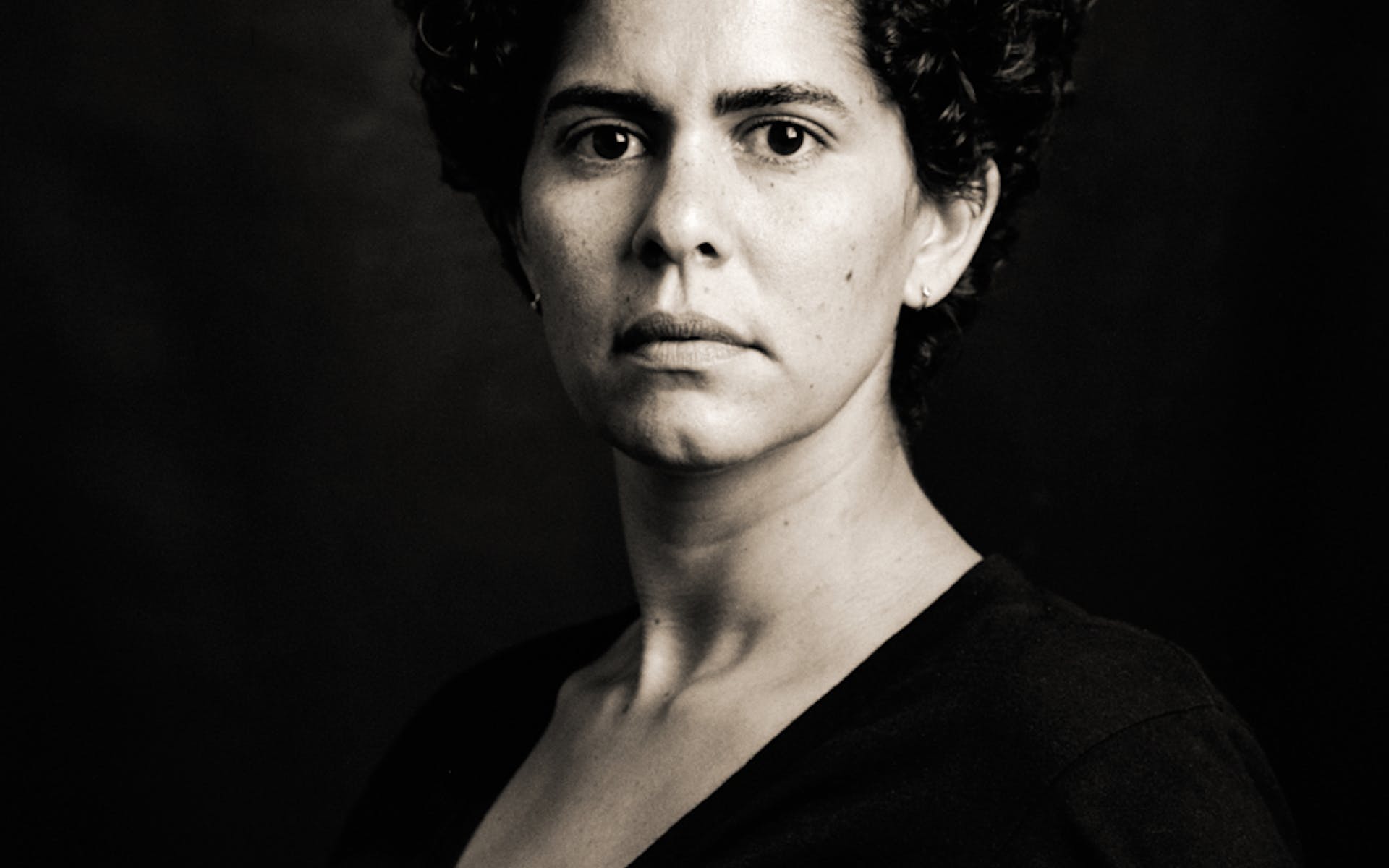 Black and white portrait of woman with black shirt on black background