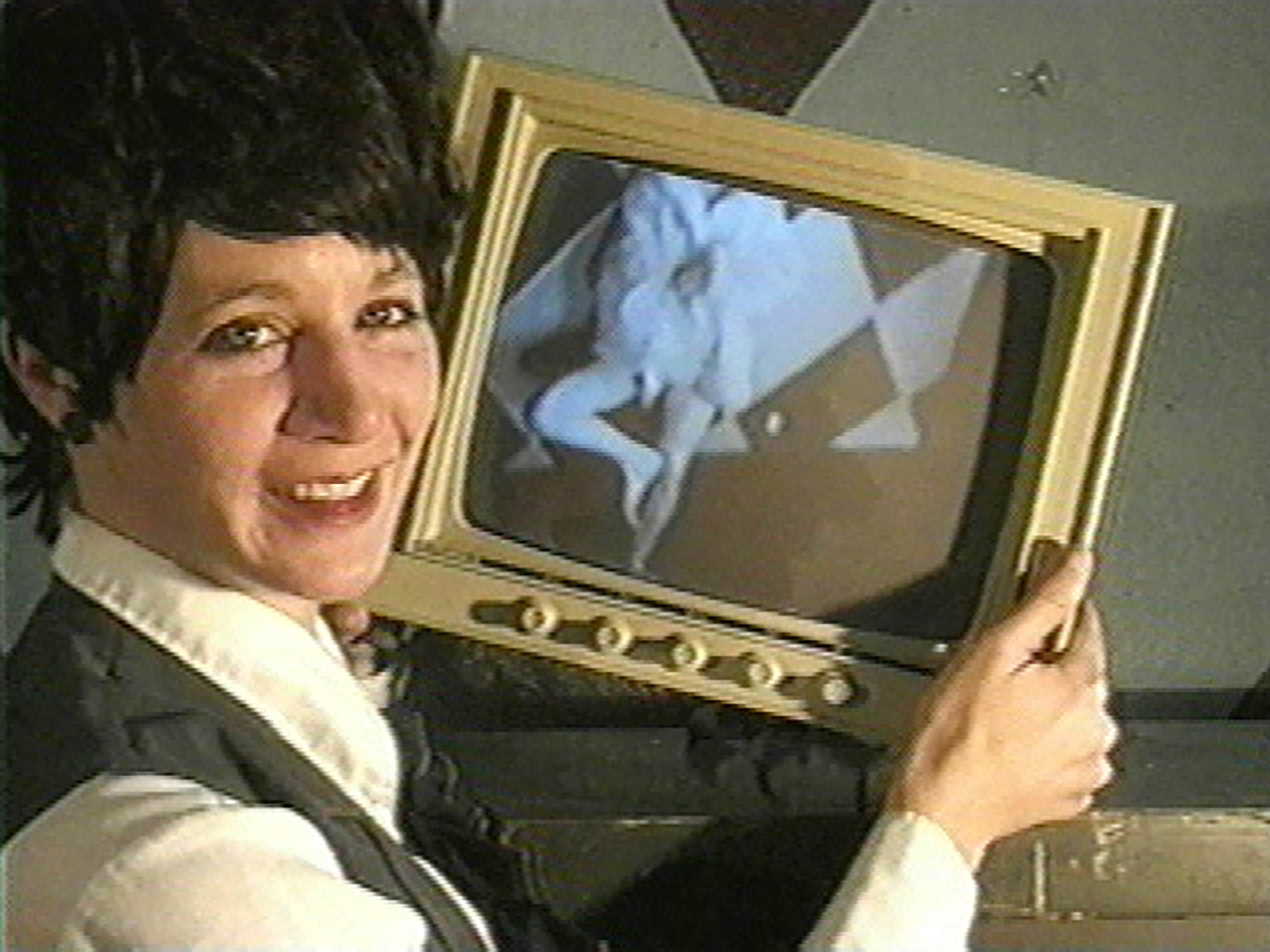 woman smiling and holding a television screen