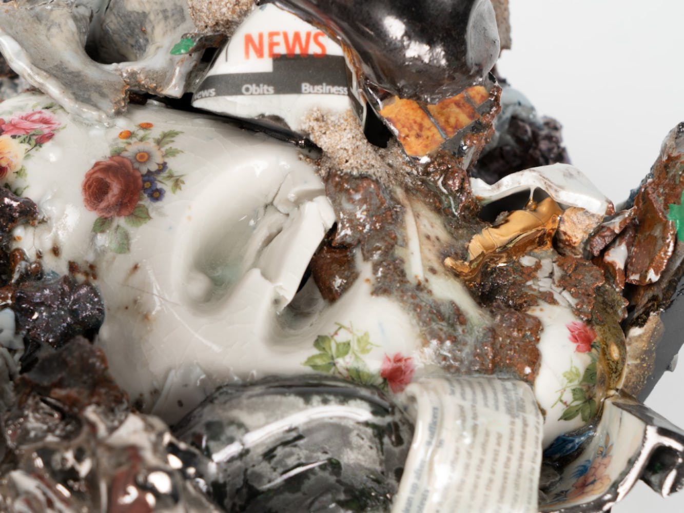 Detail of a cermaic sculpture greated with many bits of found items from the street.