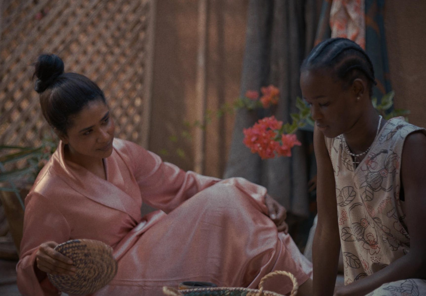 Two adults with dark skin sit next to one another on a couch.