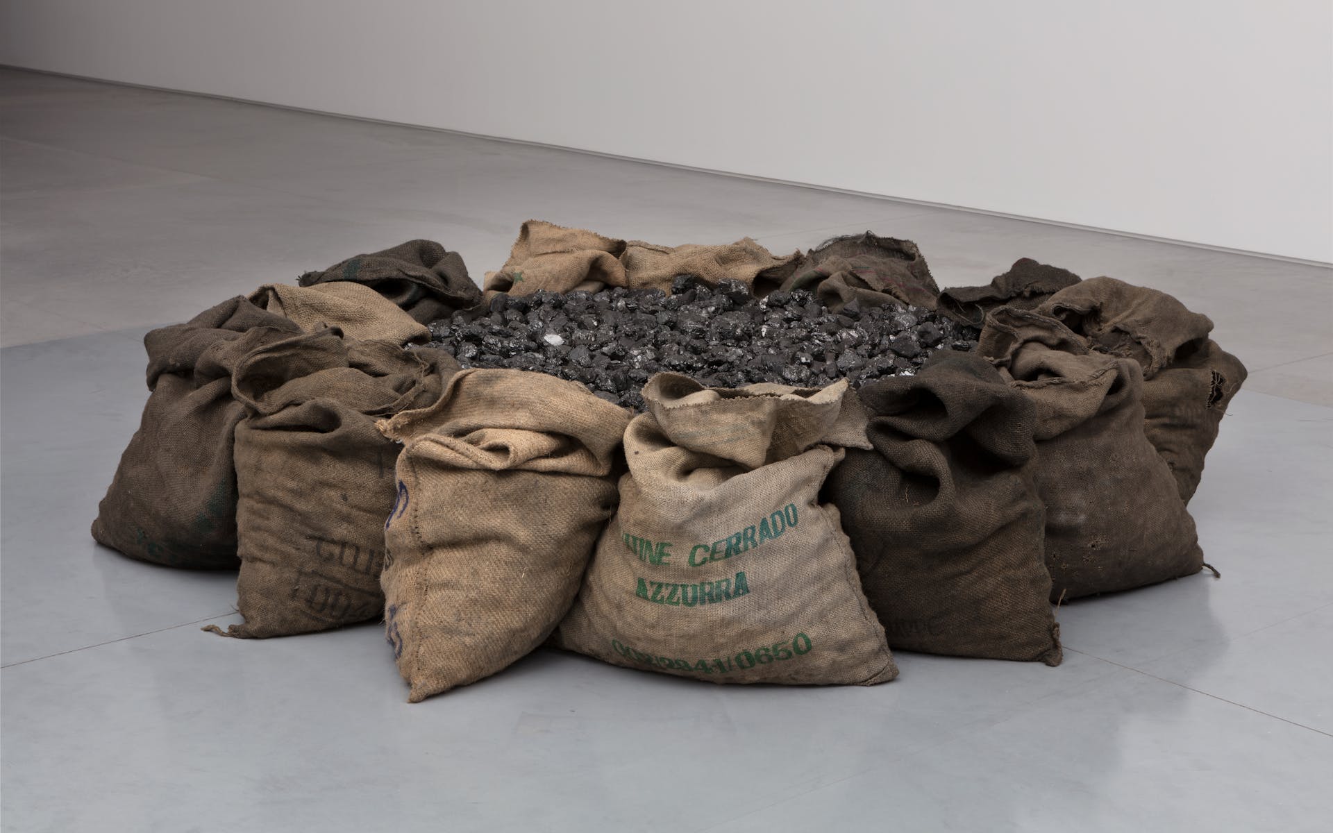 12 or so burlap sacks filled with dirt arranged in a circle in a gallery
