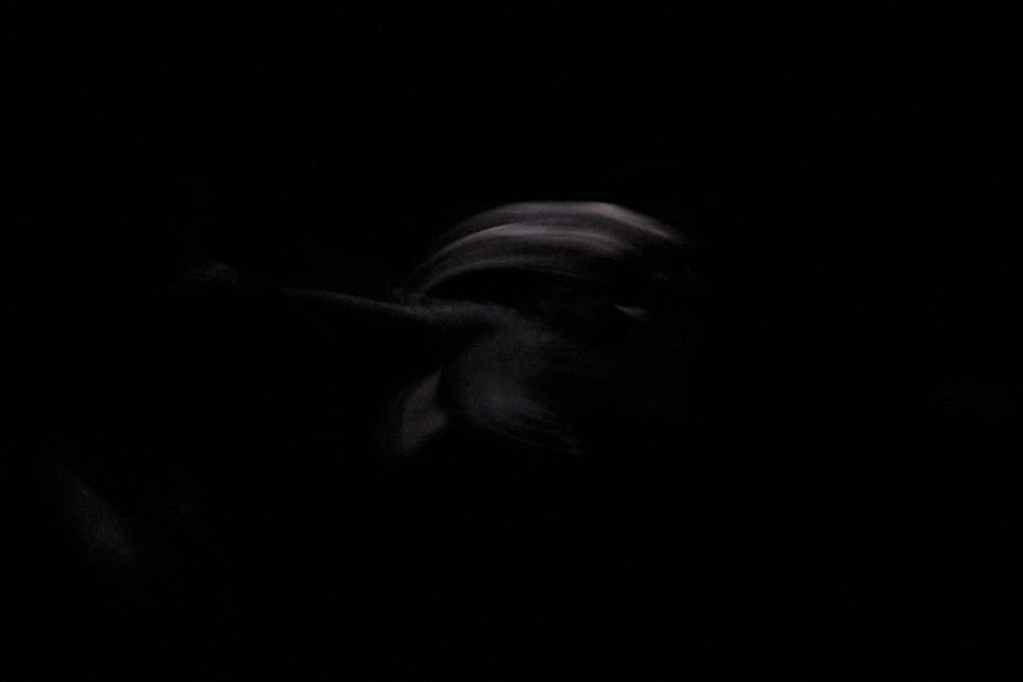 Blurry image of a woman in movement on a dark stage.