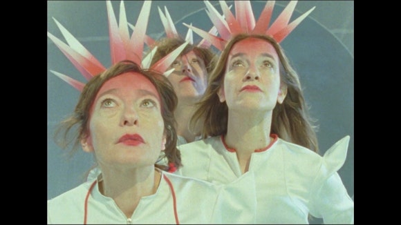 Image of three women looking upward wearing pink and white spiky crowns