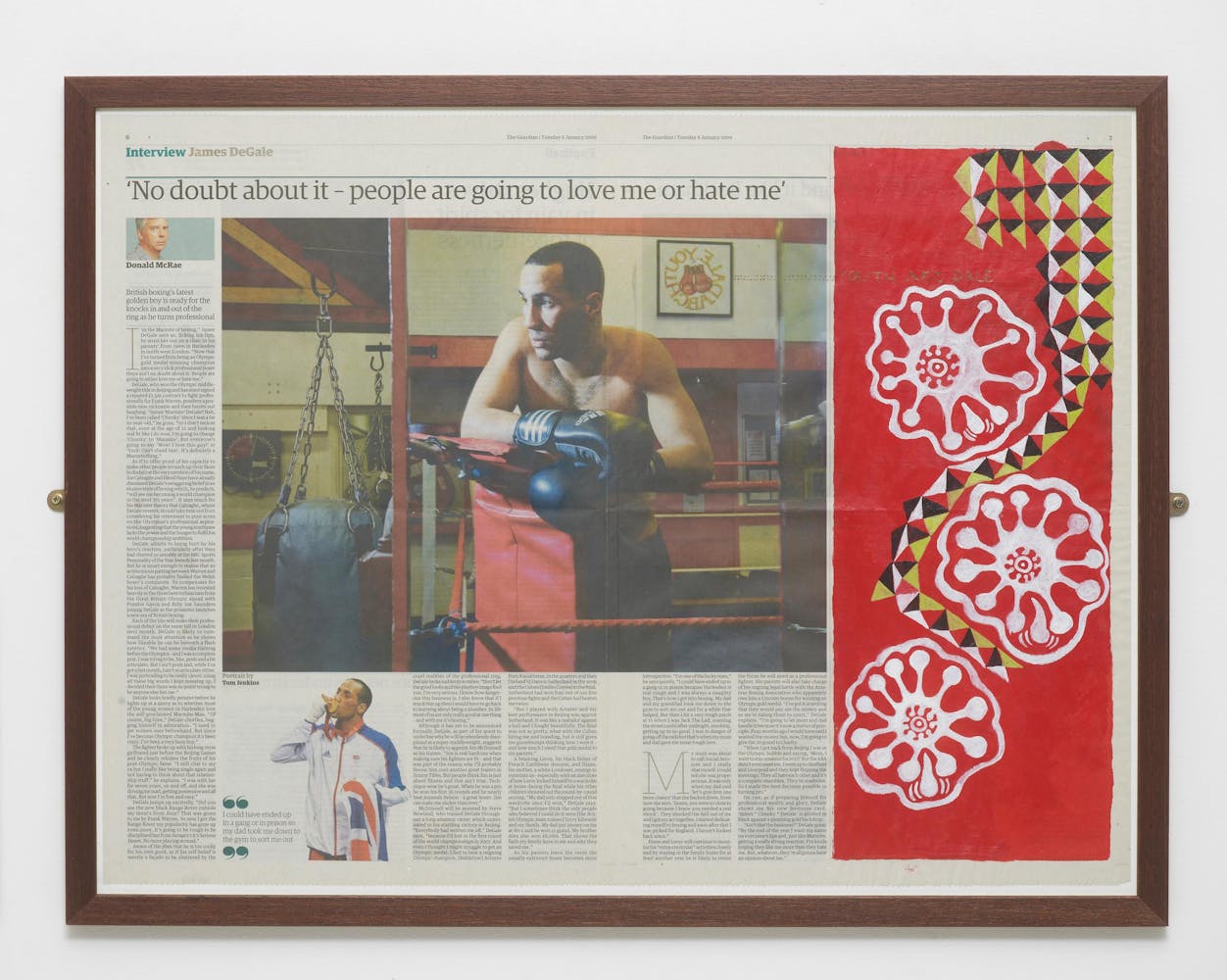 a framed newspaper with the headline 'No doubt about it - people are going to love me or hate me' above a photograph of man with dark skin wearing boxing gloves in a gym. The right side of the newspaper is painted over in red paint with a red, black, green, and white geometric design and three white floral designs