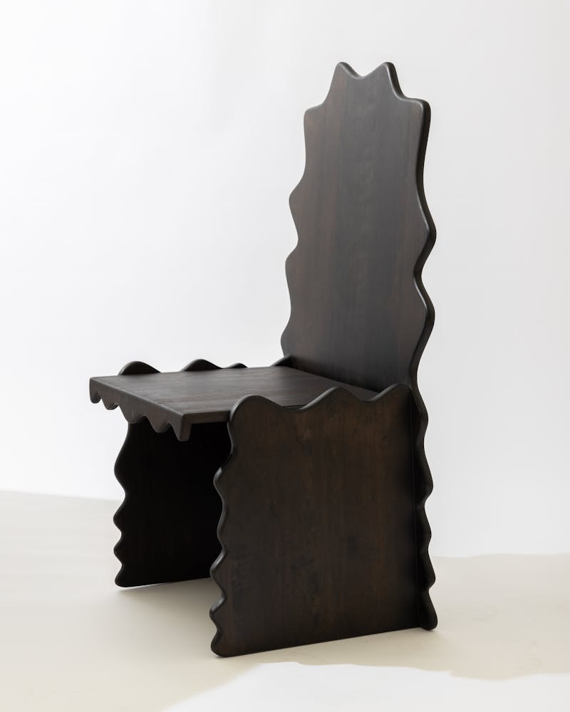 A wavy wooden chair sits in a white backdrop.