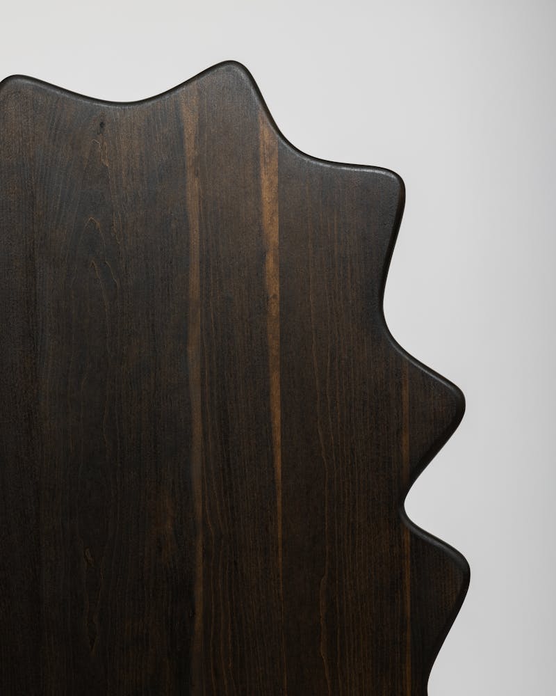 A wavy wooden chair sits in a white backdrop.