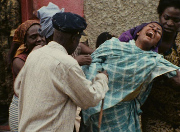 a woman yells as she’s being held back by a group of people.