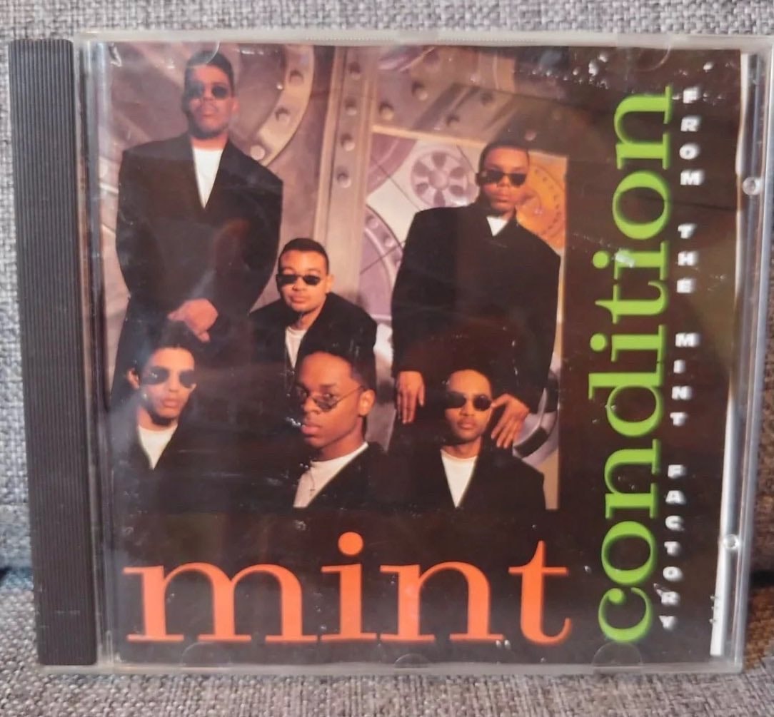 Cover of a CD with a ground of men standing together in matching black suits and sunglasses.