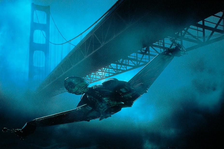 A spaceship flying under the golden gate bridge in a dark foggy blue-green scene.