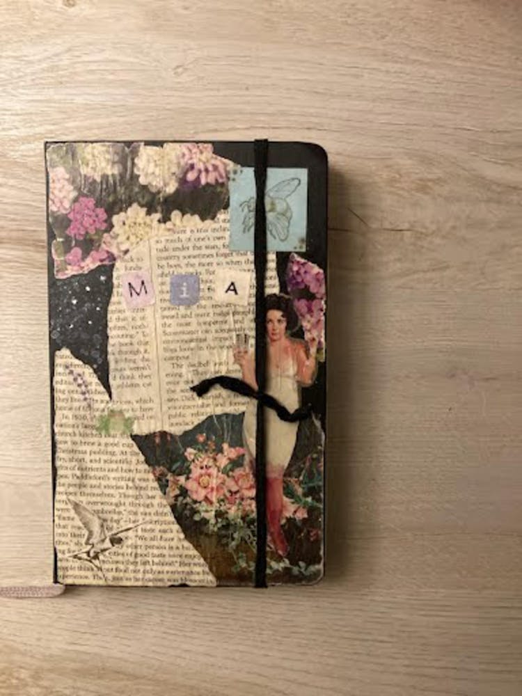 a notebook with a decorated cover laying on a wooden surface