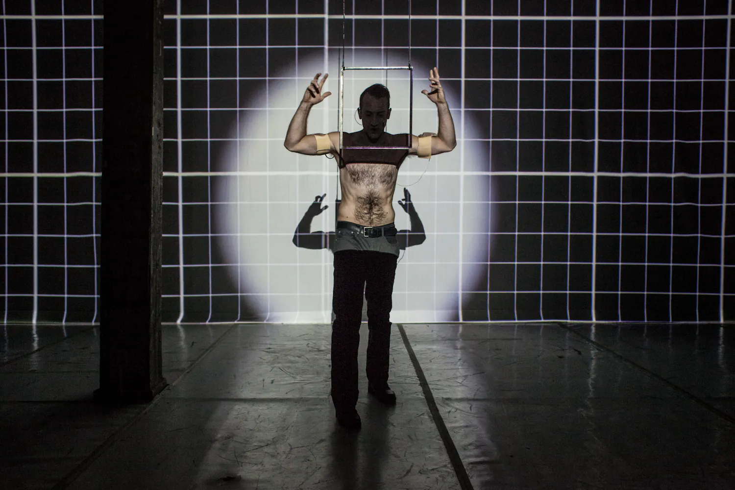 A man stands on stage with his face and neck in darkness