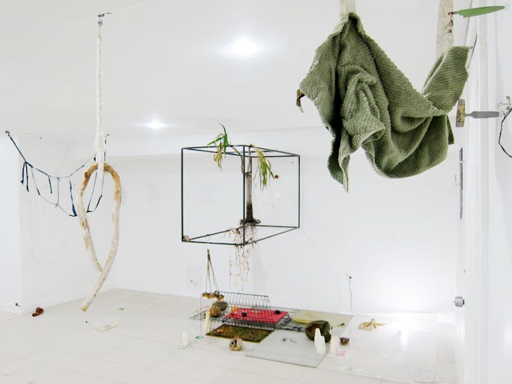 Image of various objects, frames, draped cloth hanging in a white gallery space