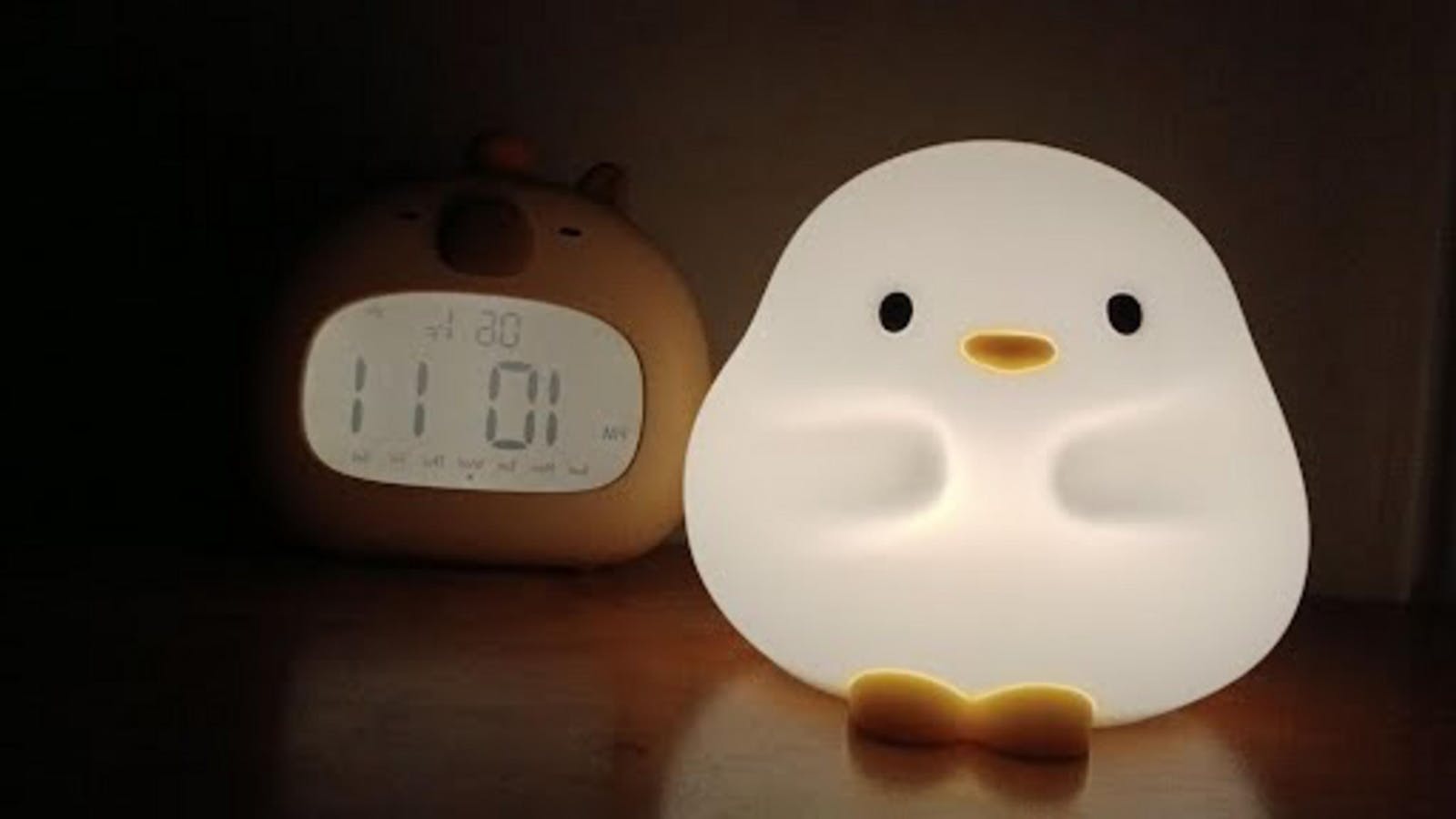 a lit duck lamp next to a digital clock