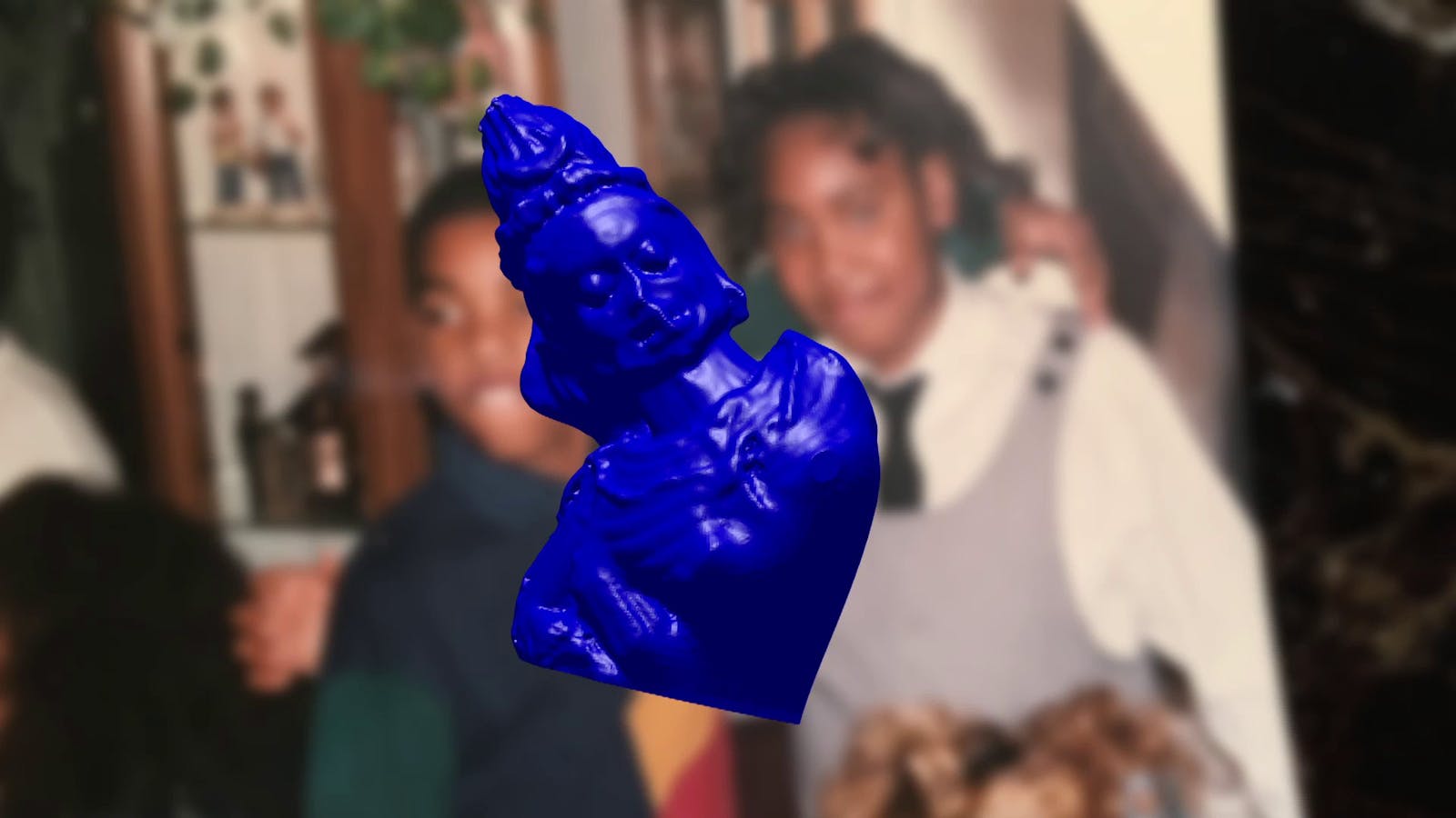 Blurred family photo in the background, with a cut out computer rendering overlaid of a cobalt blue statue.