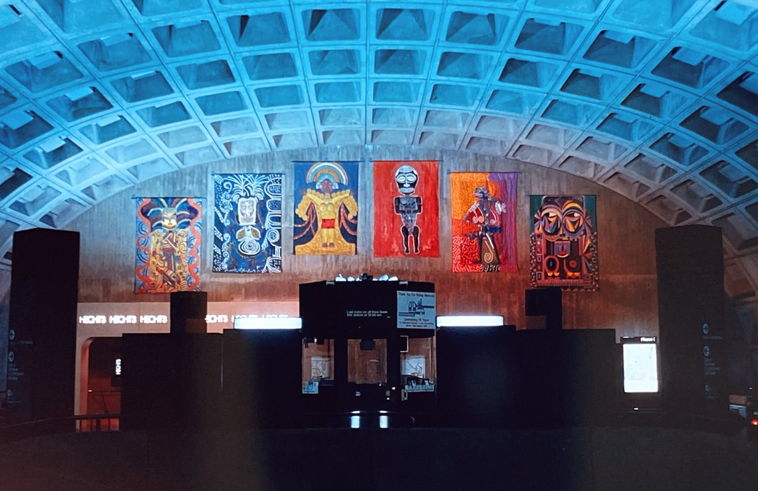 A group of large colorful paintings hanging in a large terminal.