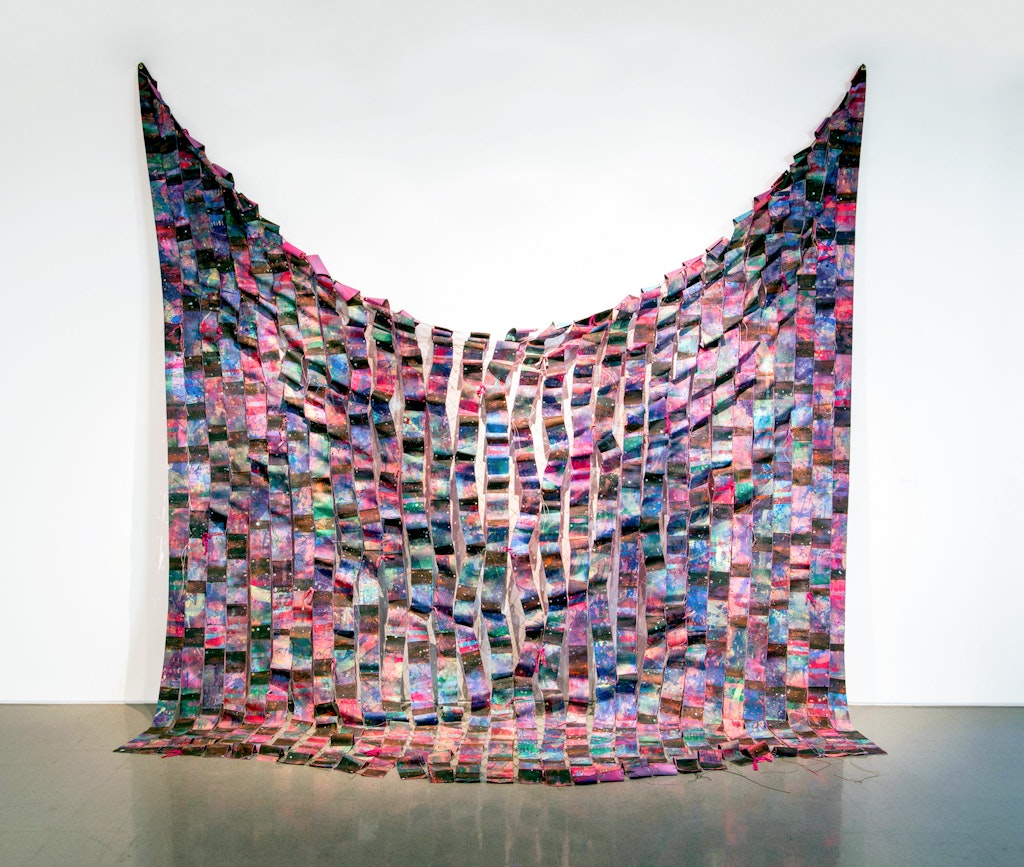 A large wall hanging of rectangular squares of fabric.