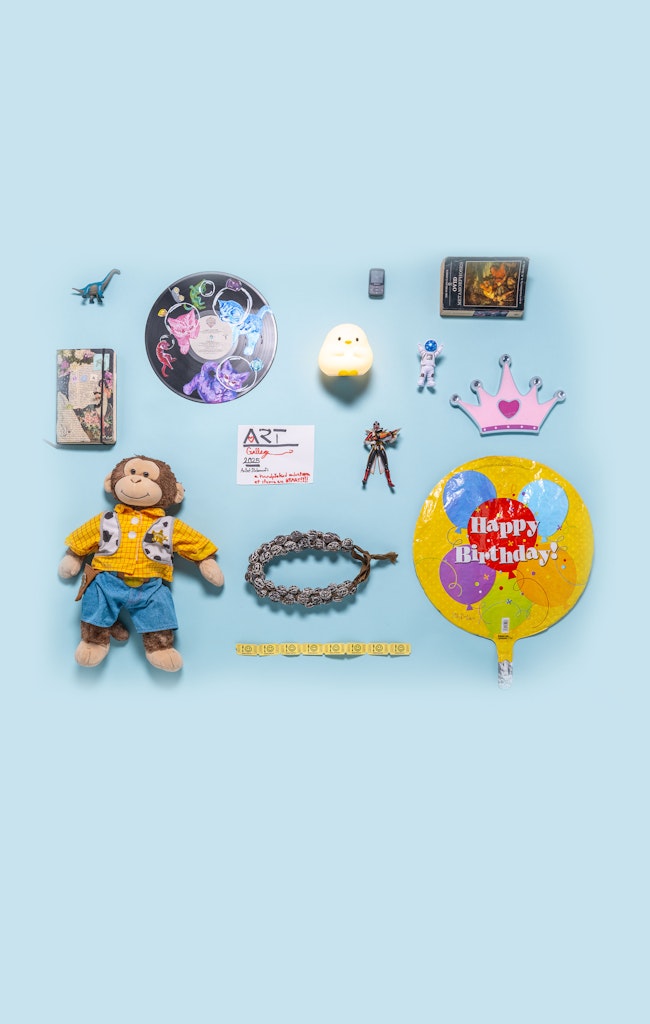 Top view of several objects, toys, a stuffed monkey, balloon, etc layed out on a blue background