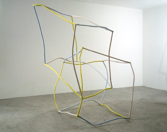 Thin crooked sculpture in the shape of two intersecting, distorted cubes in yellow and blue
