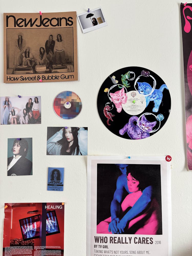 an arrangement of posters, artwork, and photos on a white wall