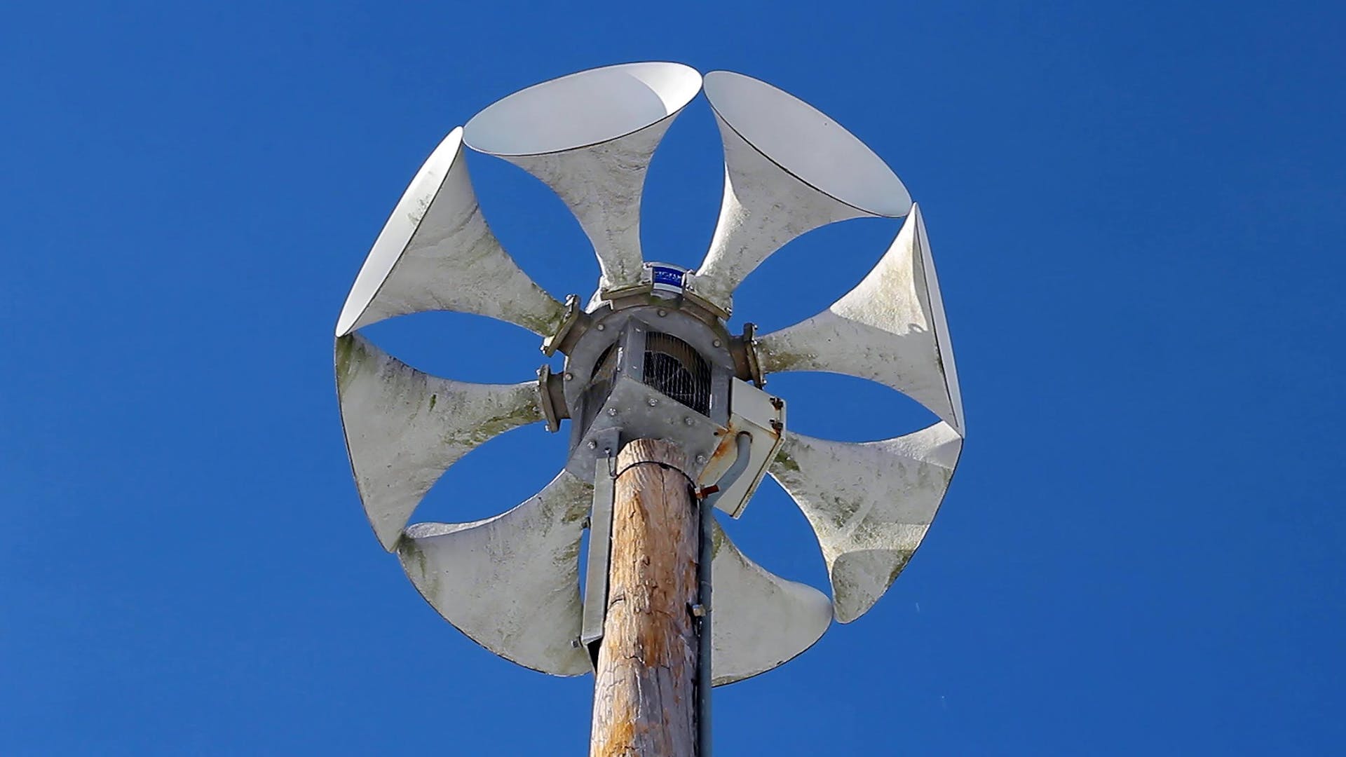 A large air raid siren on a large post.