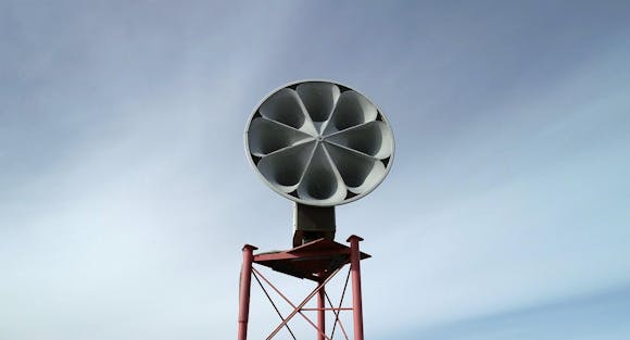 A large air raid siren on a large post.
