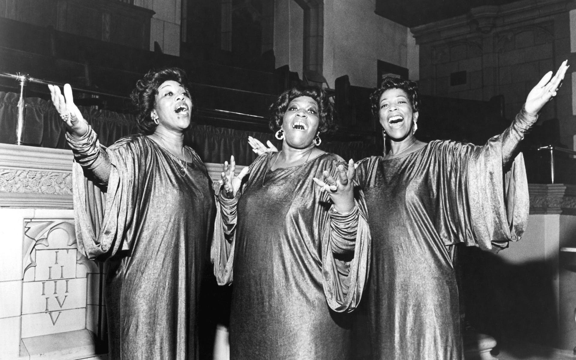 Three women in choir robes singing.
