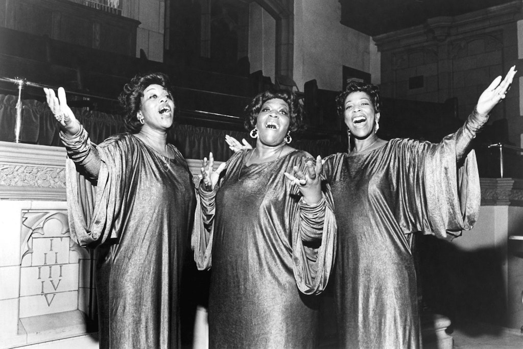 Three women in choir robes singing.