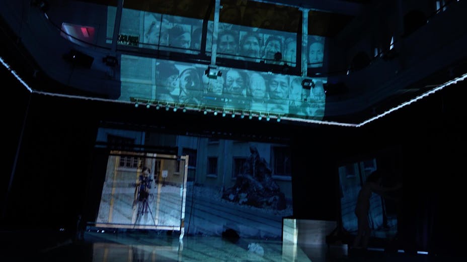 Videos are projected on the wall of a darkened theater.